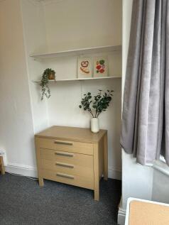 A cozy bedroom featuring a sleek wooden chest o...