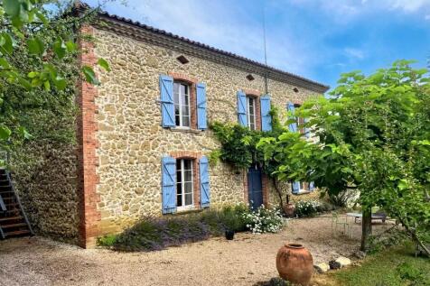 A charming stone house with blue shutters, surroun