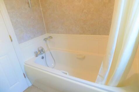 A bright and clean bathroom suite featuring a s...