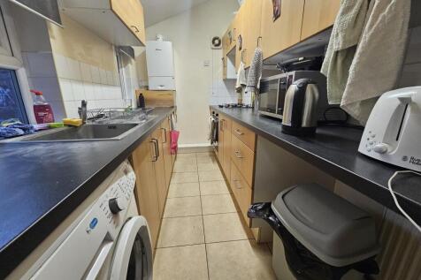 Narrow galley kitchen with black countertops, l...