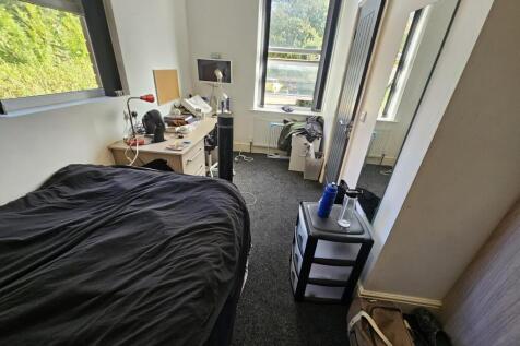 A cozy student bedroom featuring a double bed, ...