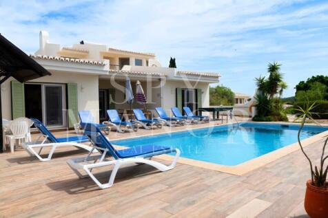 Luxury 4-bedroom villa for sale in Carvoeiro, Algarve, featuring a private swimming pool, sun loungers, and patio. Perfect holiday rental property investment near the beach.