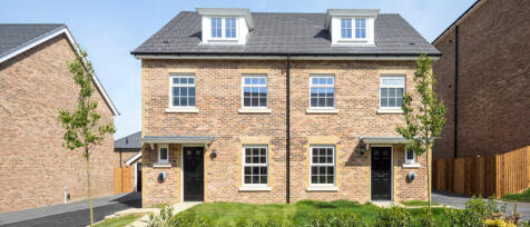 Three modern detached houses with brick and white exteriors, set in a landscaped suburban area with