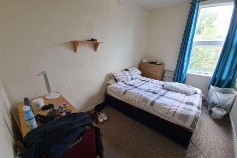 A cozy student bedroom featuring a single bed b...
