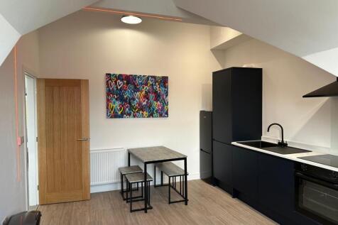 Modern open-plan kitchenette with sleek black c...