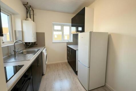 Bright galley-style kitchen with modern dark ca...