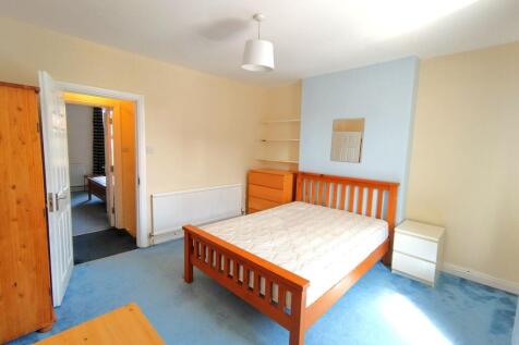 Bright double bedroom with a wooden bedframe, m...