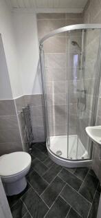 Modern tiled bathroom with curved shower cubicl...