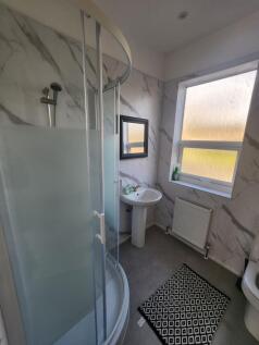 Bright, modern bathroom with a curved glass sho...
