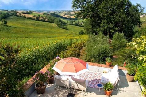 A cozy patio with a sofa and umbrella overlooks a 