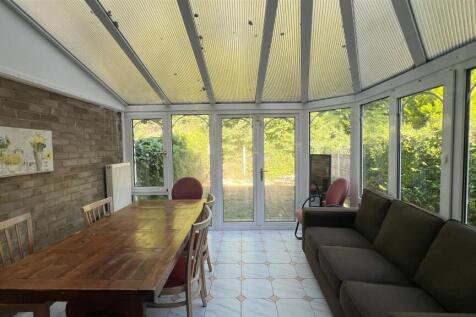 Bright conservatory with dining table and sofa...