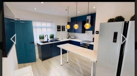 Bright modern kitchen with navy blue cabinetry,...