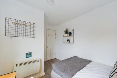 A neat, simply furnished bedroom with bright wh...