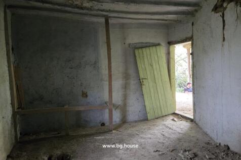 Interior room with bare walls and a wooden door leaning open to the outside.