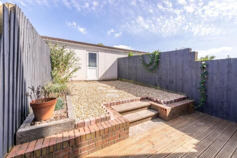 Sunny low-maintenance backyard with raised grav...