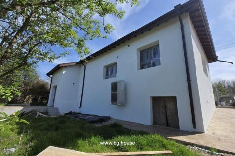 View of the white renovated house exterior showing new windows and an air conditioning unit mounted on the wall