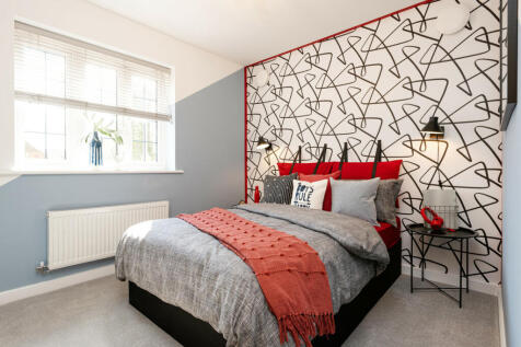 A modern bedroom features a bed with a coral throw in the foreground