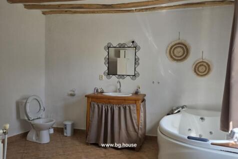 Bathroom featuring a white toilet, basin with curtain, corner bathtub, and radiator under window.
