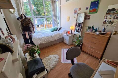 A cozy and well-lit single bedroom featuring a ...