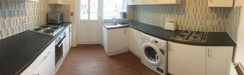 Bright galley kitchen with dark worktops, integ...