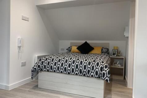 Neat, modern bedroom with patterned bedding and...