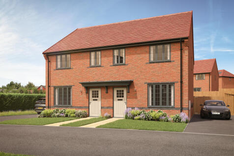A pair of modern brick semi-detached houses with manicured lawns and driveways sit under a bright bl