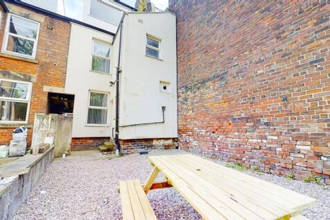 Walled courtyard with a picnic bench on gravel,...
