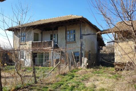 Exterior view of a traditional two-storey Bulgarian house with wooden balcony and tiled roof