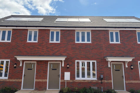 Two identical brick townhouses with gray doors and white-framed windows stand under a bright blue sk