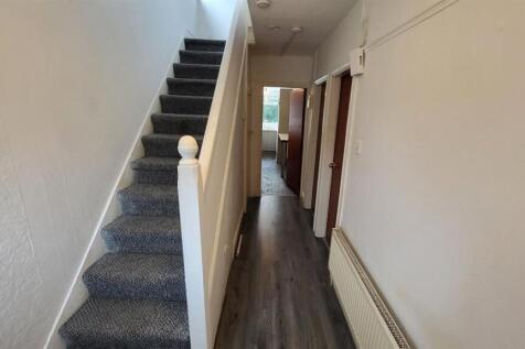 Bright, long entrance hallway with a carpeted s...