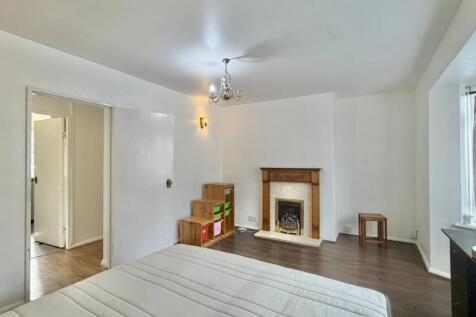 Spacious bedroom with fireplace and wooden floo...
