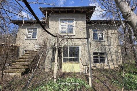 View of the two-storey house with external stairs and multiple windows, surrounded by leafless trees.
