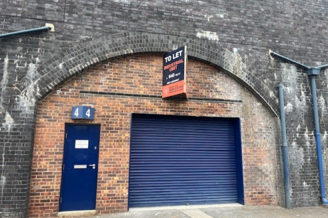 The front of an arch with a closed electric roller shutter entrance big enough for vehicle access, and separate pedestrian door.

