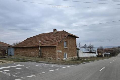 View of the brick house with tiled roof located at a street corner in Katselovo village
