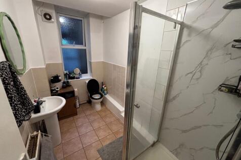 Bright bathroom with a walk-in shower featuring...