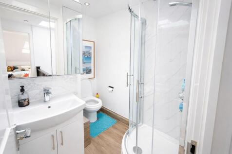 Bright, modern bathroom with a curved glass sho...