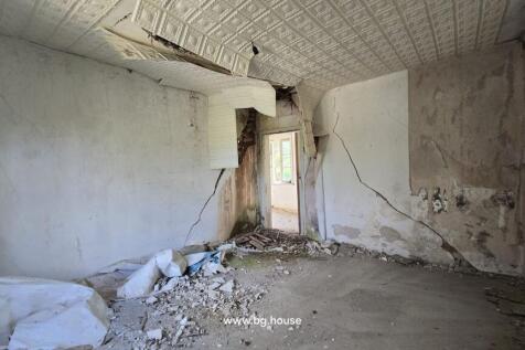 Room interior with damaged ceiling tiles, rubble on the floor, and cracked walls