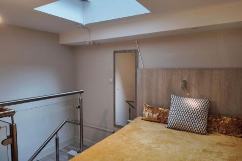 Bright mezzanine bedroom with a skylight, moder...
