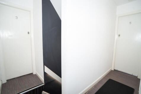 Bright, clean communal hallway with numbered do...