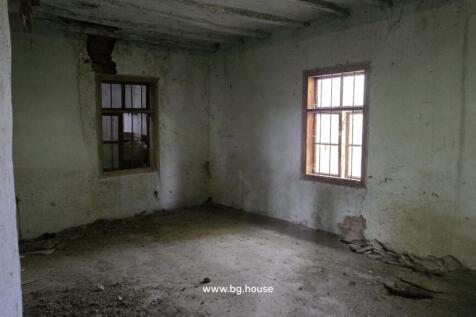 Interior room featuring two barred windows, concrete floor, and bare walls with some damage.