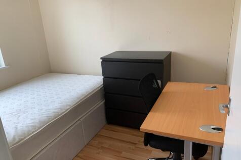 A tidy single bedroom with a comfortable desk a...