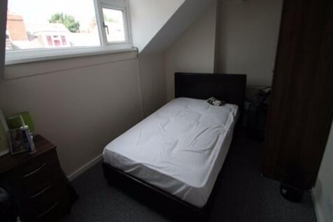 A neatly made master bedroom with a comfortable...