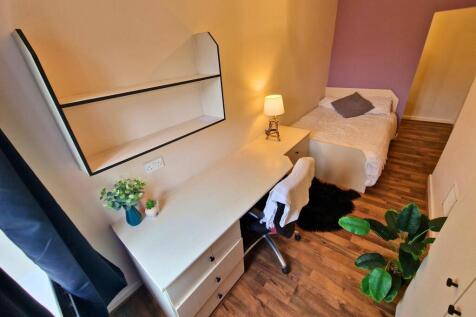 Bright, neatly furnished single bedroom with a ...