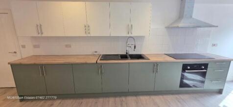 Modern kitchen with sleek units and wood surfac...
