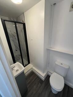 Compact bathroom featuring a modern shower with...