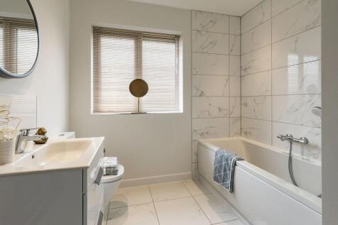A modern and minimalist bathroom with a white marble-tiled wall, a gray vanity unit
