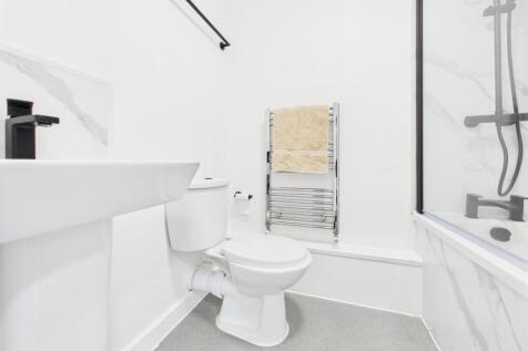 Bright, modern bathroom with a white suite, bat...