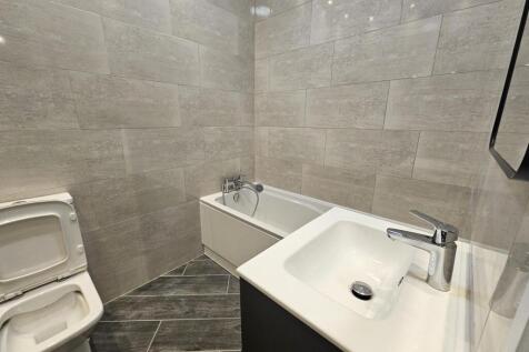 Modern bathroom with matching grey tiled walls ...