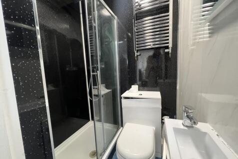 Modern compact bathroom with a glass-enclosed s...