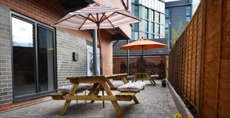 Sunny paved courtyard with wooden picnic benche...